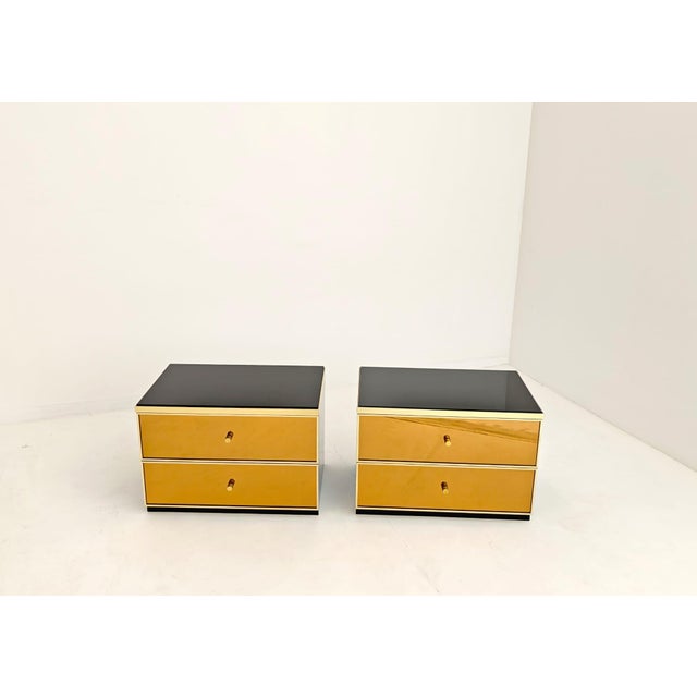 Set of two bedside tables attributed to Renato Zevi, 1970s Black lacquered wood frame, dark glass top, and two bronze-...