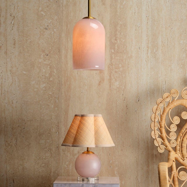 Suspended from a delicate yet solid antique brass rod, this pendant lamp features a hand-blown glass shade in soft pink...
