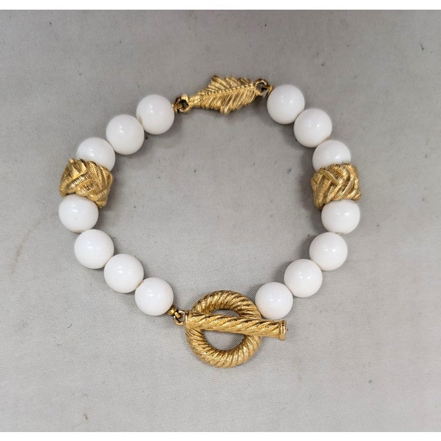1980s goldtone spherical white resin breads with "braided" goldtone beads and a single goldtone leaf bead in the center...