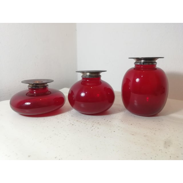 Set of three ruby ​​red Murano glass vases with a hallmarked 925 Sterling Silver rim. The color is beautiful and deep, as...