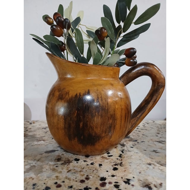 A vintage carved wood pitcher in the style of David Auld. Carved from a solid piece of olive wood with an attached handle....