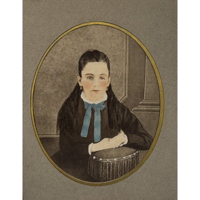 A striking vintage walnut-framed portrait featuring a hand-colored oval image of a young girl, presented in a richly...