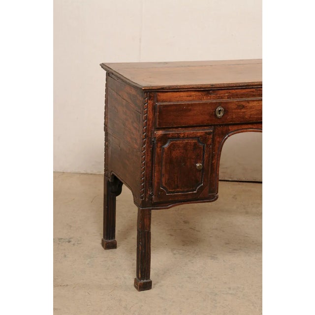 An Italian smaller-sized carved-wood desk, with pull-out writing shelf and storage, from the 19th century. This antique...