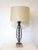 A welded iron satin black bodied table lamp with a fish bone motif sitting on a wooden base with brass detail . Topped...