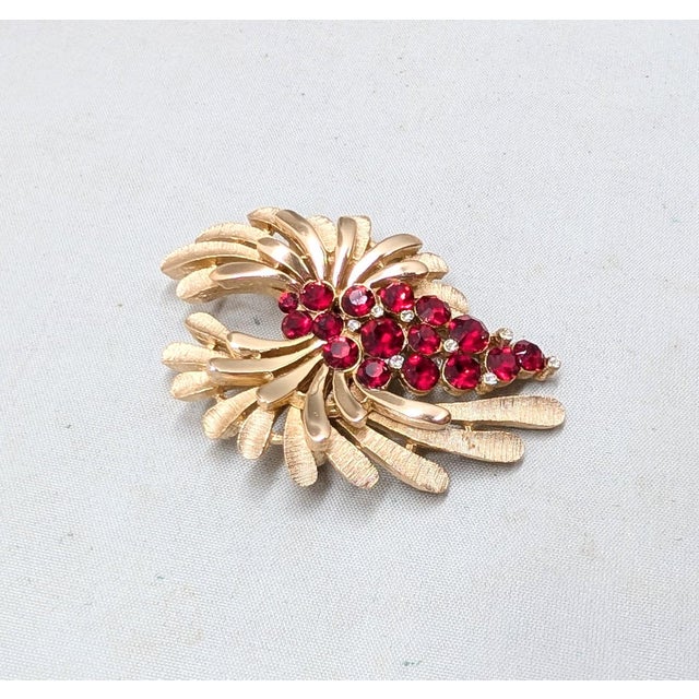 1960s goldtone round faux-garnets and small round clear rhinestones brooch with security clasp. Marked crown "TRIFARI©."...