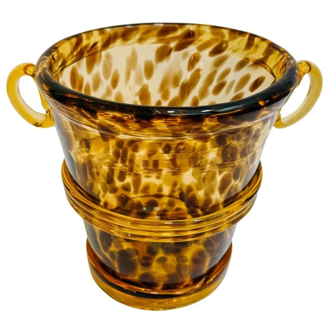 A hand-blown glass ice bucket featuring a classic tortoiseshell (or leopard spot) motif, achieved by suspending deep amber...