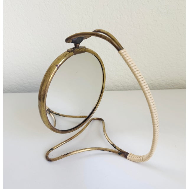1940s Italian-style articulating shaving mirror made of aged brass with splayed base and rattan-like wrapped arm. Mirror...