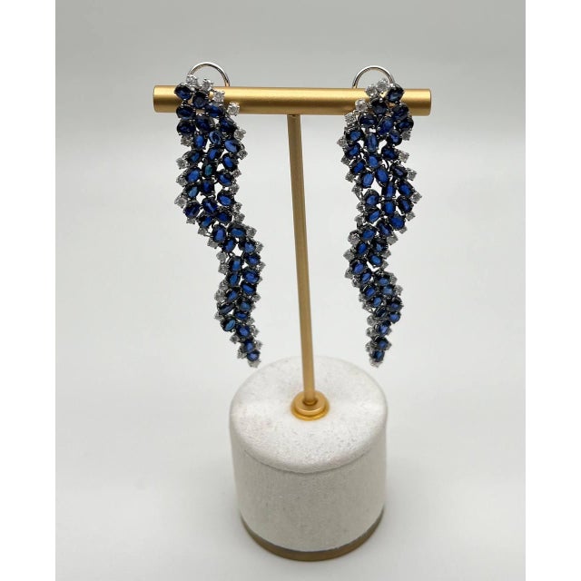Discover the elegance of these exquisite earrings. Crafted with a cascade of deep blue sapphires, these earrings create a...