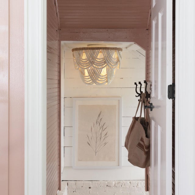 Cascading layers of soft-distressed white wooden beads in the Lorelei provide a graceful display over a jute-wrapped...