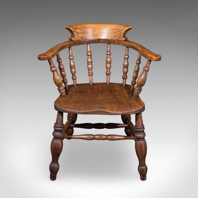 This is an antique country house captain's chair. An English, beech and elm smoker's bow or elbow seat, dating to the...