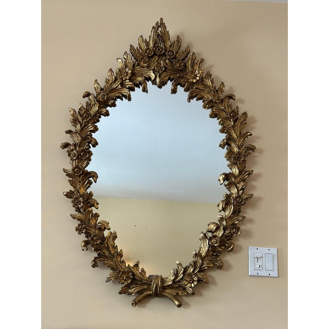 Mid-century Italian carved giltwood wall mirror by Florentia, featuring an exuberant stylized floral and leaf motif. A...