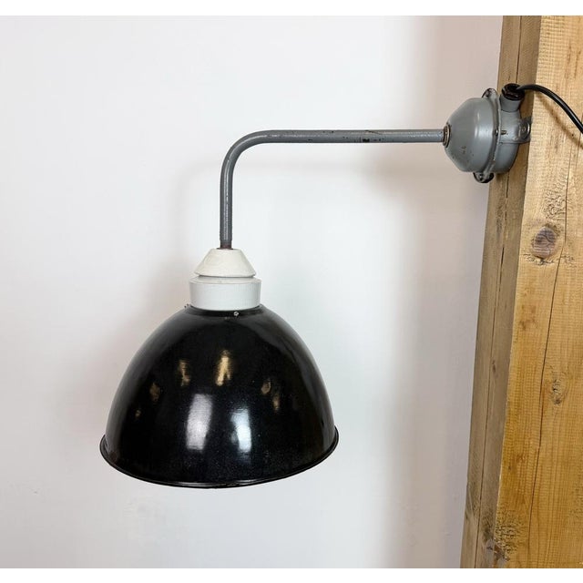 Industrial factory wall light made in former Czechoslovakia during the 1960s. It features a grey iron wall mounting and...