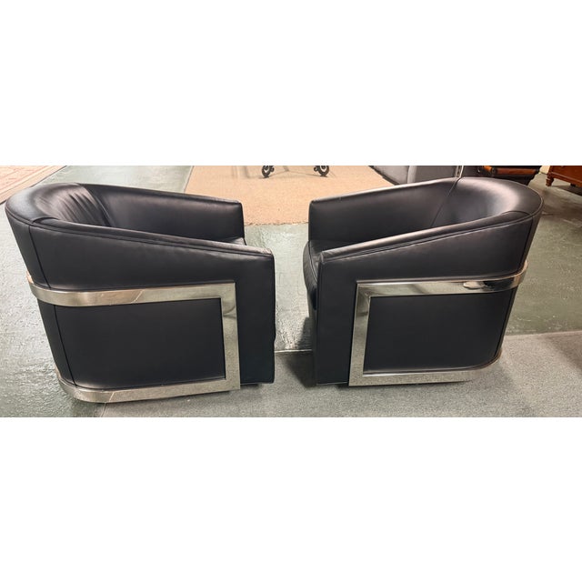 Pair or Restoration Hardware black leather swivel lounge chairs featuring sleek polished chrome frames and a low-profile,...