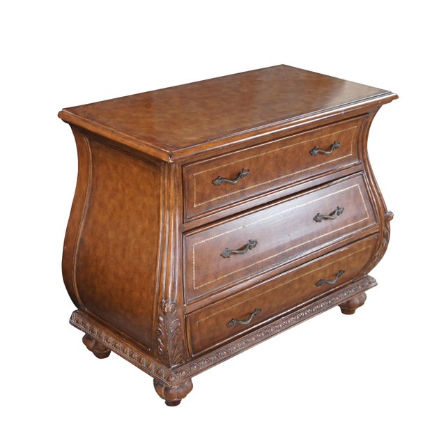 Vintage French Louis XVI style bombe dresser / chest of drawers featuring a tooled leather design with acanthus accents....