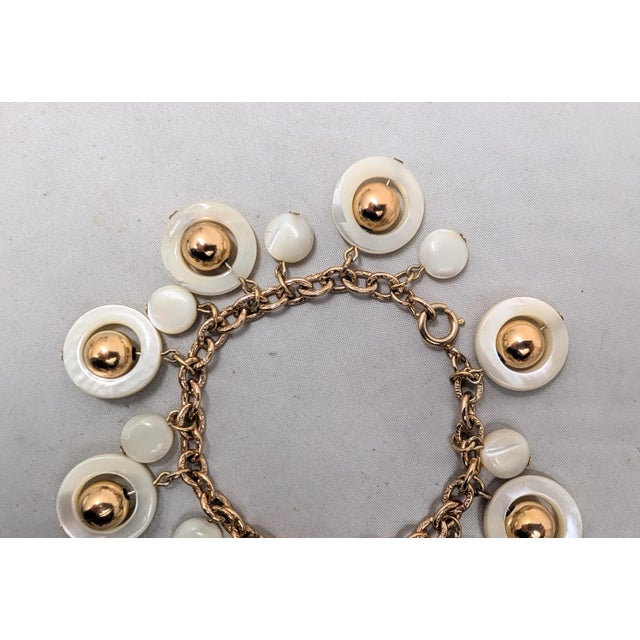 Late 1970s or early 1980s goldtone mother-of-pearl discos with balls inside them and flat circular mother-of-pearl charms...