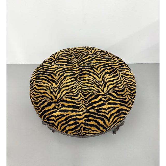 A bold vintage round ottoman upholstered in eye-catching tiger print velvet, featuring a deeply tufted cushion that adds...