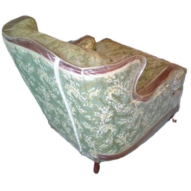 This vintage wingback armchair exhibits a classic French-Provincial style characterized by its ornate, hand-carved wood...