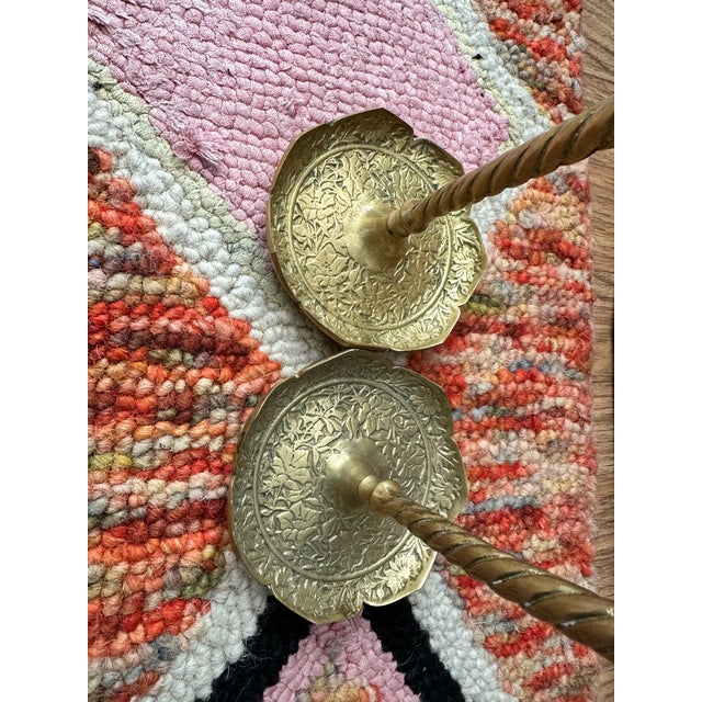 Elegant pair of tall hand-tooled brass candlesticks featuring a twisted stem, scalloped floral base, and embossed vine...