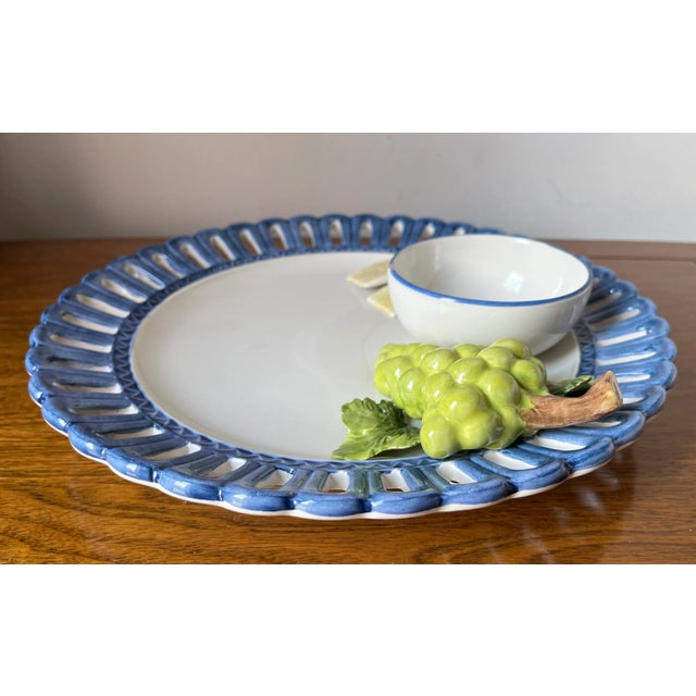 This wonderful Hand-painted faience chip & dip platter features 'Tromp L'oiel' cheese and grapes and a sauce or dip...