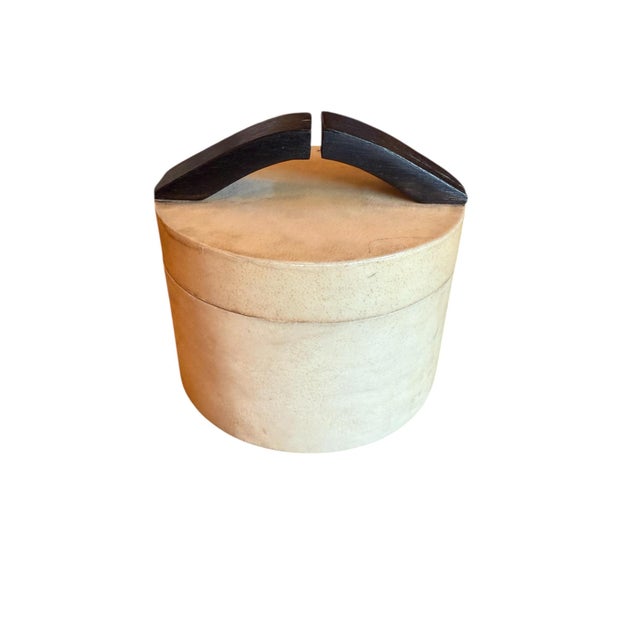 Round box from R&Y Augousti. Handmade turned wooden box is covered in a cream parchment and topped with a segmented...