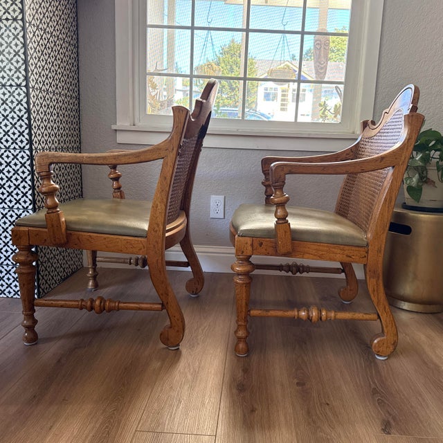 (2) Vintage French Provincial dining armchairs were manufactured by Drexel Furniture and feature rustic wooden frames with...