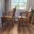 (2) Vintage French Provincial dining armchairs were manufactured by Drexel Furniture and feature rustic wooden frames with...