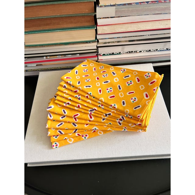 Set of 12 vintage cotton napkins in a bright golden yellow with a playful geometric print in red, purple, green, and...