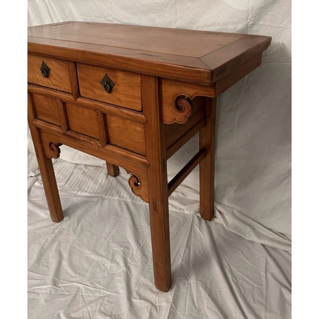A beautiful and useful table made of light elm wood. It has two drawers.