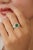This cocktail ring showcases a 1.24 ct round-cut emerald, set in 14K yellow gold. The emerald measures 8 mm, beautifully...
