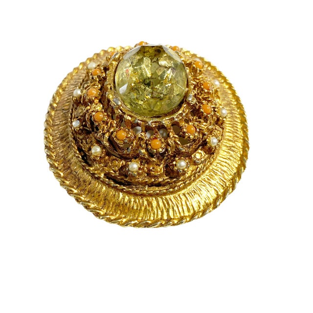 This Vintage Brooch features an elegant Gold Tone with a large, centered Topaz Rhinestone and a mix of round-shaped white...