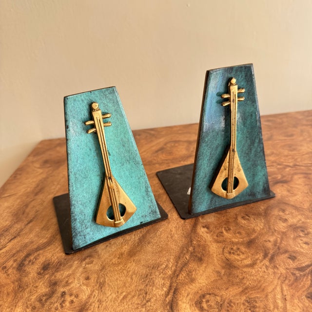 A pair of faux copper verdigris finished bookends. Enameled and brass lyre on a metal base. Signed Oppenheim and Israel....