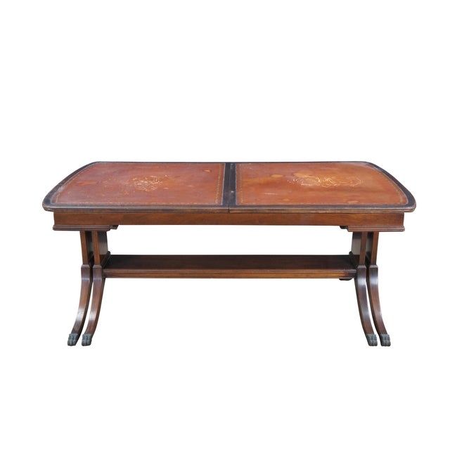 An intriguing mid 20th century Duncan Phyfe style extendable coffee table. Made from mahogany with a brown tooled leather...