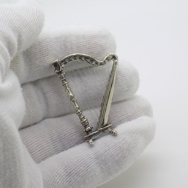 A vintage miniature depicting a musical harp, handcrafted in silver in Italy between the 1970s and 1980s, representing the...