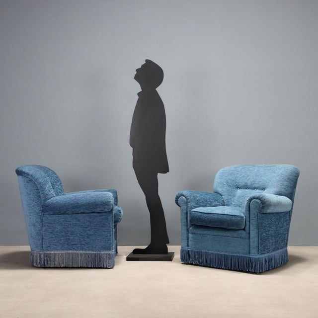 Pair of armchairs with sprung padding, velvet upholstery, decorative fringe along the perimeter. This piece is attributed...