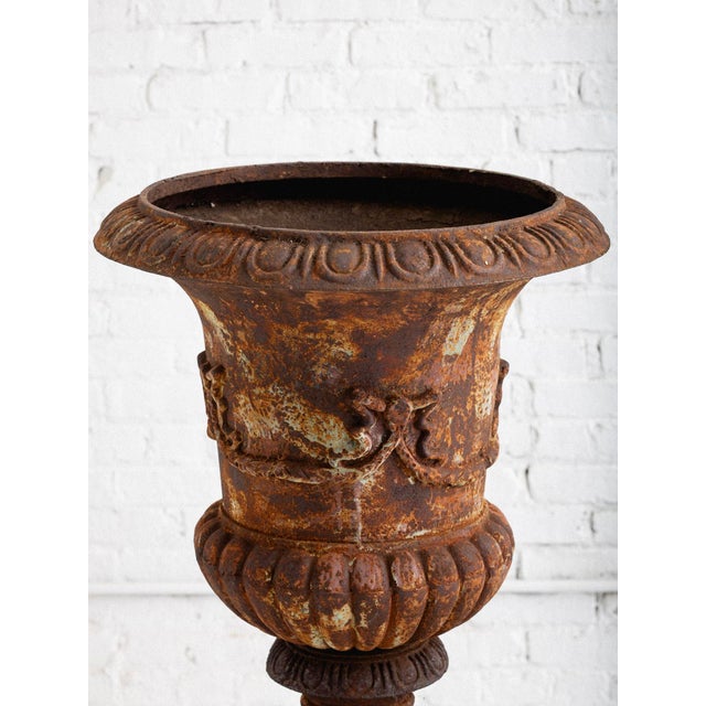 A pair of large 19th century cast iron garden planter or “Medici Urn.” Decorative bow detail. Rust patina with remnants of...