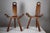 Pair of mid century brutalist tripod side chairs in light tinted wood, with hand carved details on the handles. Both are...