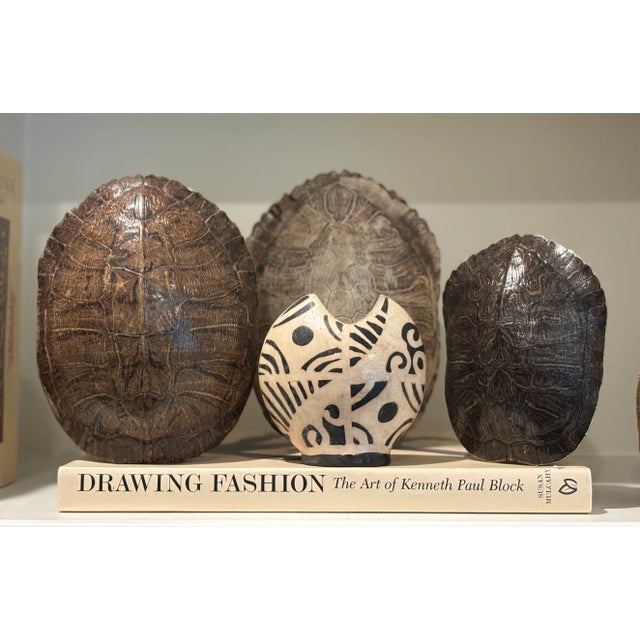 This sculptural handcrafted earthenware vase features a notched-rim form and bold dark brown-on-cream geometric/tribal...