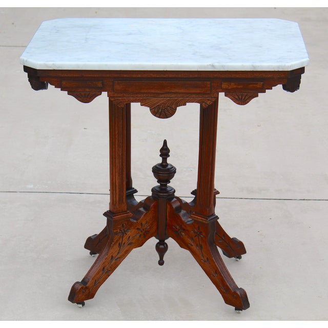 A beautiful late 19th-century American Victorian Eastlake marble top parlor table featuring a richly carved walnut base...