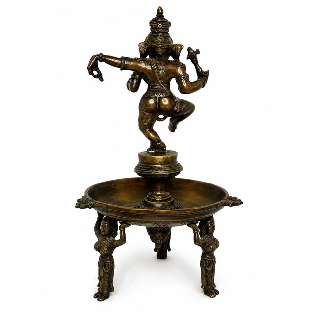 A striking decorative sculpture depicting Lord Ganesha in an expressive dancing pose. The figure features intricate...