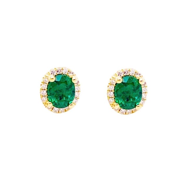 These stunning post back earrings feature a natural oval-shaped emerald weighing total approximately 6 carats, accompanied...