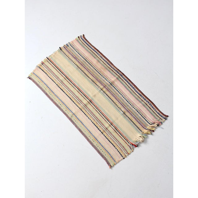 Vintage hand-loomed accent rug with a softly striped pattern in buttery yellow, pale pink, gentle green, and clear blue...