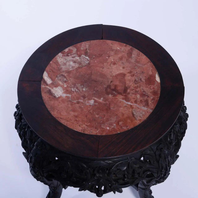 An antique Chinese plant stand offers inset marble top over hardwood base having pierced and carved foliate skirt, raised...