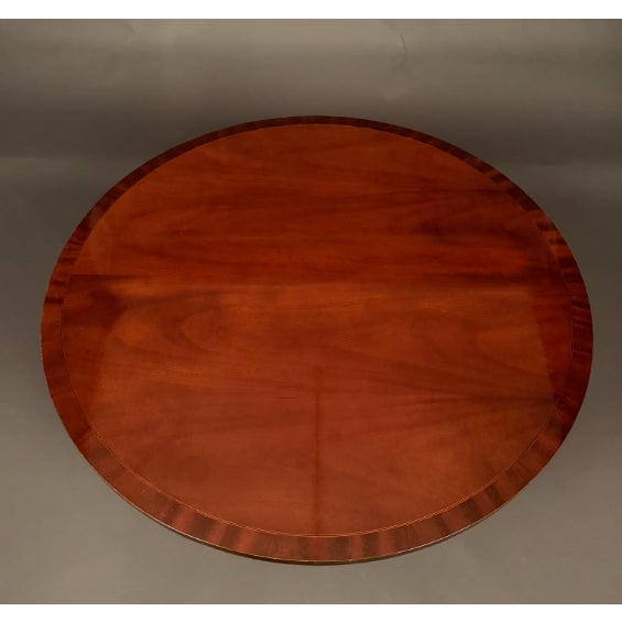 Mahogany pedestal base coffee table by Councill Craftsmen featuring satinwood and ebony inlay. The table is supported by a...