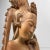 Delicately carved wooden sculpture of a woman with graceful features, her head gently bowed as a small bird – a...