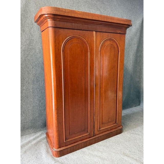 This 19th century mahogany two-door wardrobe showcases a refined, understated design with arched panel doors and a warm,...