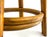 A sculptural bentwood stool featuring a warm rattan frame with gracefully curved legs and a circular stretcher base. The...