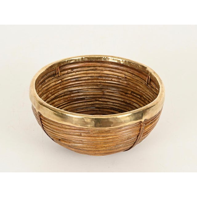 Wonderful Mid-Century round decorative bowl or basket in curved rattan, wicker, and brass. This stylish organic piece was...