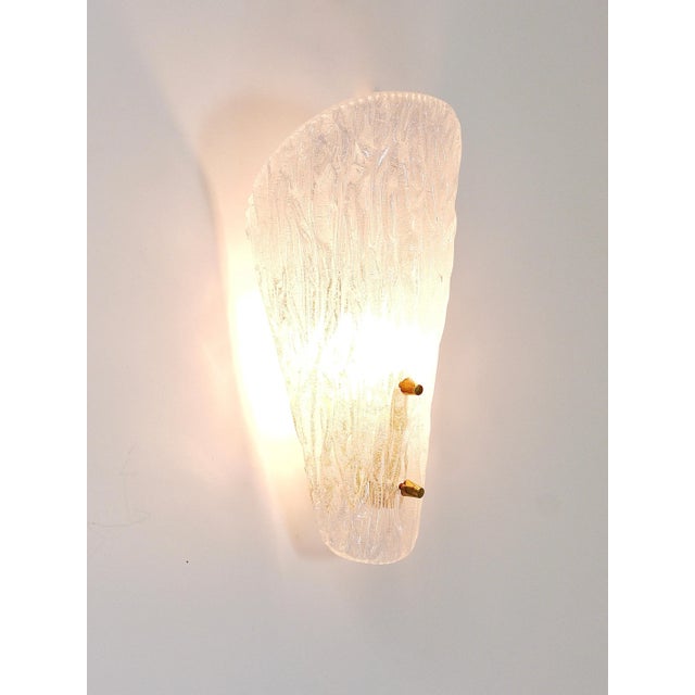 A single beautiful brass wall light with a lampshade made of solid textured melting ice glass with nice knobs....