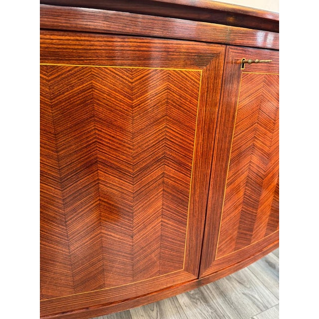 A fine dark cherrywood bow fronted two doos credenza with striking chevron inlay pattern standing on tapered legs with...