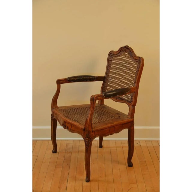 Elegant caned Louis XV period walnut armchair, circa 1760. Leather armrests.